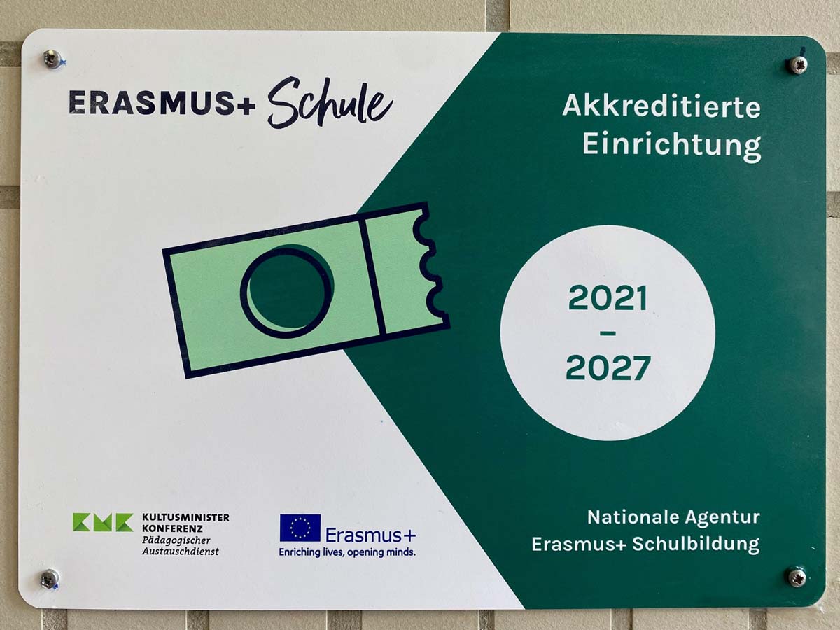 Frontalaufnahme des Erasmus+ Auszeichnungsschildes an der Wand im Schulgebäude