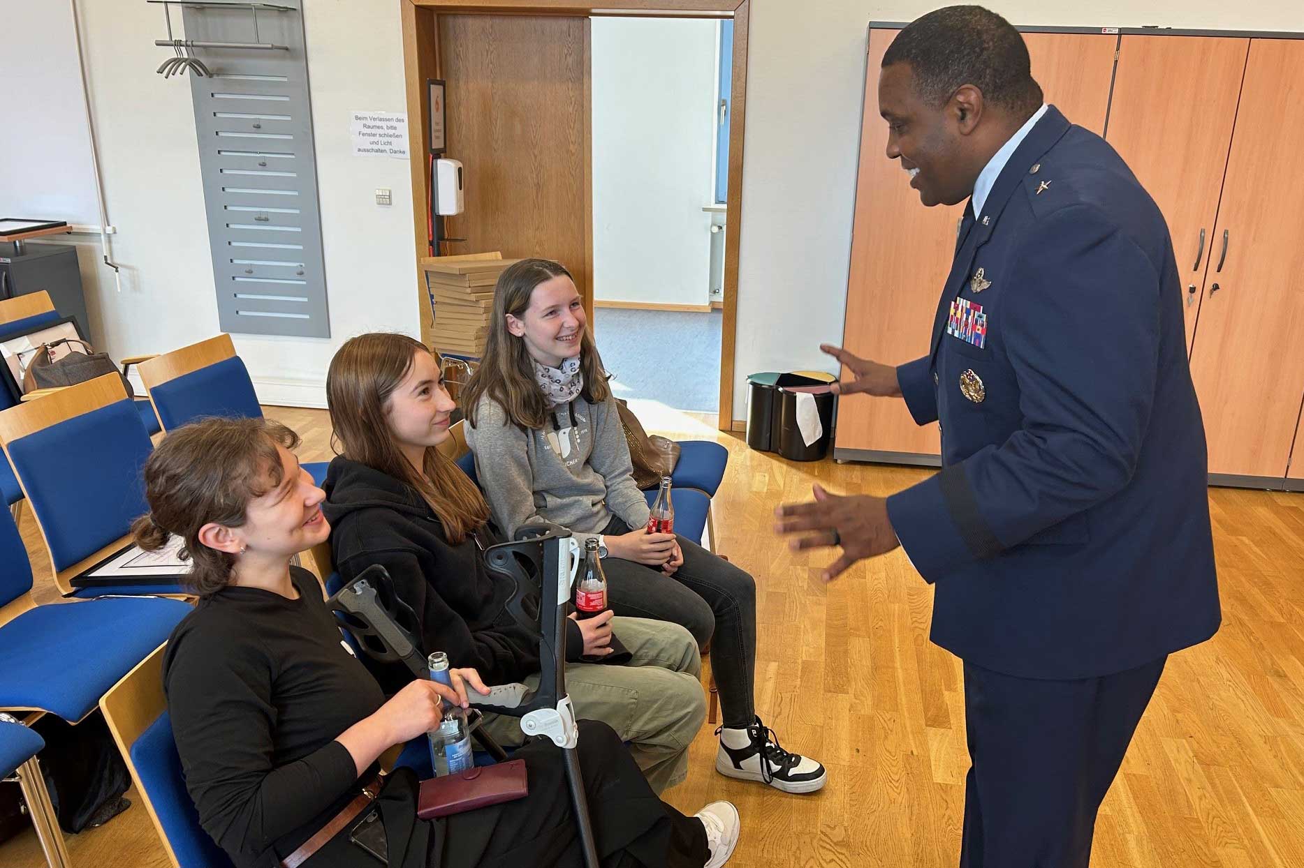 Schüler sitzen vor einem amerikanischen Soldaten in Uniform im Rahmen der Auszeichnung als WiR Schule